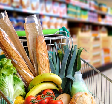 Winkelwagen met boodschappen zoals stokbrood, banaan en tomaten